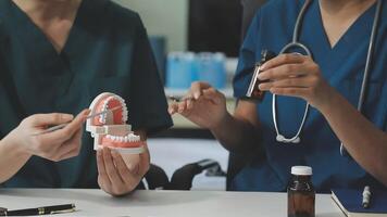 Two nurses working with a model of a tooth video