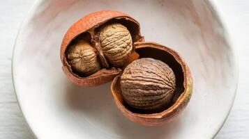 Two walnuts in a bowl on a white surface photo