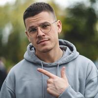 A man in glasses and a grey hoodie pointing at something photo