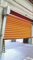Orange rolling door of the warehouse is closing. Rolettes work with the help of automation. Motion of rolling door to down Vertical video