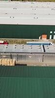 The territory of the warehouse and the factory with parquet. Wood processing plant. Aerial view. Camera motion to left Vertical video