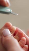 Cutting the toenails for a little baby. Caring mother using the special scissors for the procedure. Close up. Blurred backdrop. Vertical video