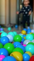 Little baby comes into the room. Toddler boy stops surprised by the multiple balls in the middle of the room. Blurred backdrop. Vertical video