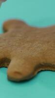 The confectionery nozzle is drawing the image of a person on the finished ginger biscuits with icing. Close-up. Christmas cookies Vertical video
