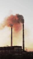 En Static view of the high-voltage tower sky background, factory pipe with smoke over it. Earth pollution and industrialization concept. Selective focus. Vertical video