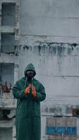 Human in respirator looking at the ruined building and preparing to the work. Ecologist in the abandoned place after biological attack concept. Vertical video