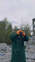 Im shocked. Ecologist in safety suit touching to his head on ruined building background. Person in gas mask and protective clothes stands in dangerous place after chemical attack. Vertical video