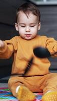 Beautiful child having fun in the kitchen. Adorable happy toddler holds the ladles playing and waving them. Vertical video