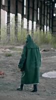 Nature in danger. Ecologist in safety suit and gas mask preparing to placing flowers in abandoned place. Biochemical attack and polluted environment concept. Vertical video