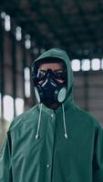 Person in chemical protective suit standing in distracted place. Survivor in abandoned place with piles of garbage from ruined buildings. Apocalypse concept. Vertical video