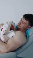 Caring father is holding newborn baby. Dad soothes his child after birth while mother is resting after C-section. Vertical video