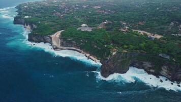 Construction and engineering on cliff coastline under Uluwatu temple in Bali. Drone view video