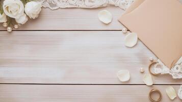 Elegant wedding stationery mockup featuring an envelope, golden rings, delicate white roses, lace fabric, and scattered petals on a rustic wooden background photo