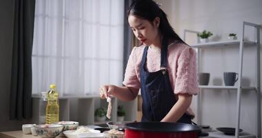 Handheld shot, Beautiful woman is preparing the process of coating chicken with all the ingredients in a bowl before frying the chicken on a pan. Cooking concept, Food preparation video