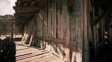 Old wooden structure with sunlit shadows in a desolate area during the day video
