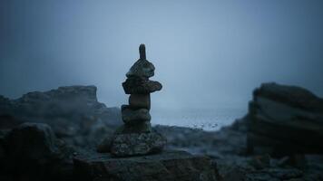 Rock formation balances atop a serene coastline at dusk video
