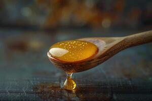 Honey dripping from a wooden spoon on a dark table photo