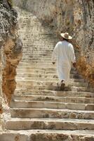 A man in white robes walking up some stairs photo