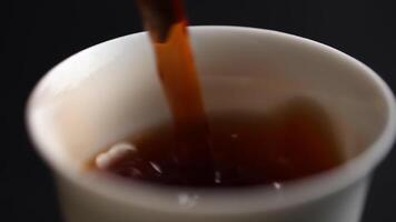 Carefully pouring a rich, dark beverage into a welcoming cup during a relaxing afternoon. Media video