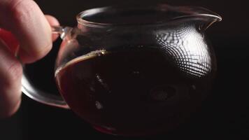 Elegant Glass Teapot with Dark Brewed Tea, an embodiment of warmth and comfort in every sip. Media video
