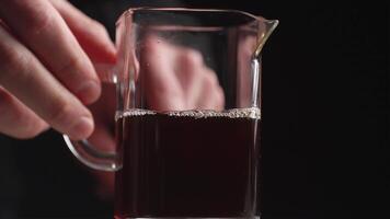 A Close Up View of a Glass Pitcher Holding a Dark Beverage Set Against a Black Background. Media video