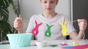 Happy Boy made Easter paper garland. Multicolored Easter bunnies on string with clothespins. Slow motion video