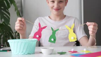 Laughing Boy made Easter paper garland. Multicolored Easter bunnies on string with clothespins. Slow motion video