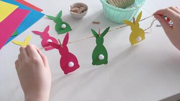 Boy made Easter paper garland. Multicolored Easter bunnies made of paper on string with clothespins, Slow motion video