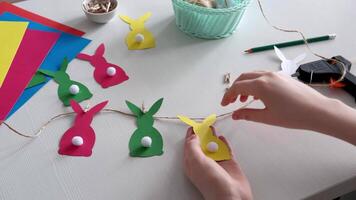 Preparing for Easter. Making diy paper garland. Hands fastening the Easter bunny to string video