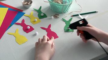 Preparing for Easter. Making diy paper garland. Hands glue the tail to the paper Easter bunny video