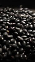 Vertical of black beans on black background, black bean seed video