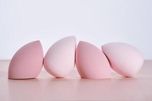 A set of makeup sponges on a pink background. photo