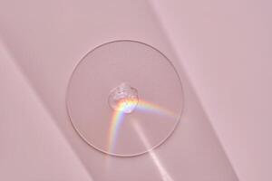 A drop of serum on a round stand on a pink background with beautiful caustics. photo