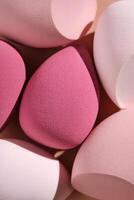 A set of makeup sponges on a pink background. photo