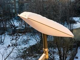 SpaceX's Starlink satellite dish is covered in snow. Starlink is disabled and does not melt snow. View from the apartment window photo