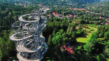Aerial view of Sky Walk spiral observation tower in Sweradow Zdroj, Poland, surrounded by green forests. Popular tourist attraction with breathtaking panoramic views of surrounding mountains video