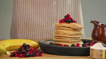 Stack of hot, classic American pancakes, drenched in maple syrup and dusted with powdered sugar, is prepared for breakfast by chef at restaurant. video