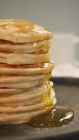 Syrup or honey, dripping down sides of stack of classic American pancakes, creates thick and gooey consistency, enhancing sweet and cloying taste of breakfast. video
