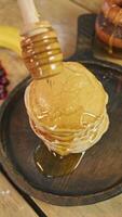 Rotating honey dipper, from which maple syrup or honey gracefully drizzles onto stack of pancakes adorned with berries, creating ambiance of classic American breakfast. video