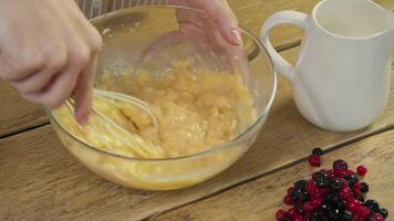 In a traditional kitchen, the egg yolk is mixed with flour using a whisk in a bowl. Close up. high angle video