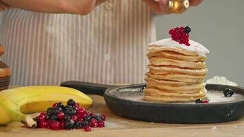 Fresh berries and jam are topped on a tall stack of delicious, juicy, freshly made hot pancakes, adding a sweet touch to the baking. video