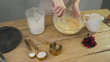 The cook actively mixes flour with egg yolks while creating blueberry pies or pancakes with berries. video