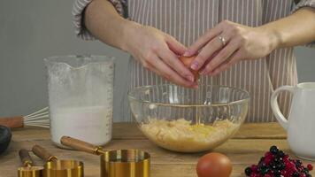 During preparation of the dough, pastry chef in kitchen carefully breaks an egg and adds yolk to flour, in order to give it more density and viscosity. video