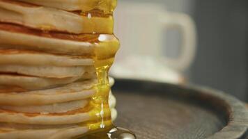 Maple syrup or honey dripping down side of stack of traditional American pancakes, creating viscous and sticky texture, adds sweet and cloying flavor to breakfast. video