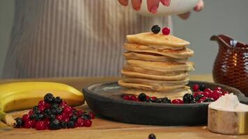 Handful of berries, such as cranberries or currants, are placed on top of delicious stack of hot, fresh pancakes. These berries perfectly complement flavor of traditional breakfast and add touch of sweetness and brightness. video