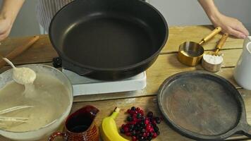 In restaurant's kitchen, chef prepares delicious American pancakes using a traditional recipe. They add mixture of flour and eggs to hot pan to create the pancakes. video