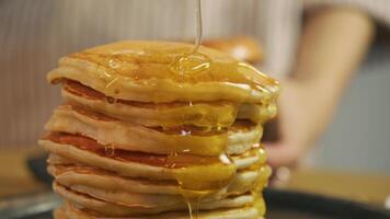 Traditional American breakfast of pancakes, with maple syrup or honey, stacked on top of each other, generously drizzled with golden syrup. video
