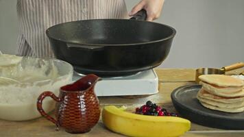 The cook puts a mixture of flour and eggs onto a hot frying pan, which is placed on an electric stove, to make pastries or pancakes. video