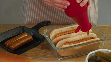 A portion of hot dogs for two is poured with ketchup in a diner before serving to a customer in the kitchen. video