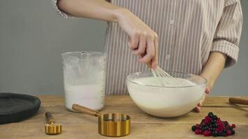 Pastry chef kneads dough with flour and egg, creating base for pie filled with blueberries and cranberries. scene takes place in rustic kitchen. video